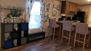 Eine moderne Küche mit Holzausstattung, einem schwarzen Kühlschrank und einer Bar mit Barhocker.