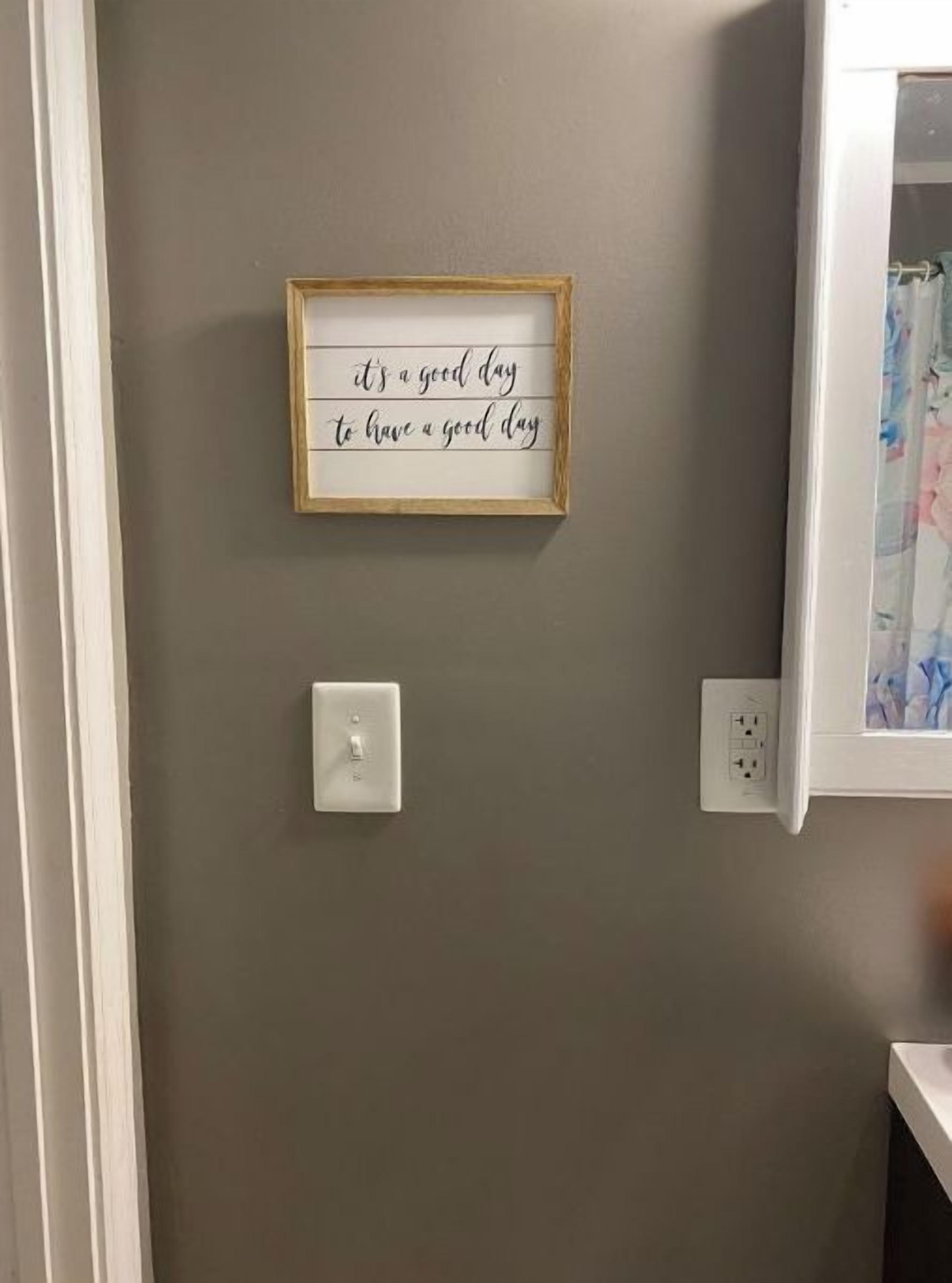 Una cita inspiradora enmarcada en la pared de un baño.
