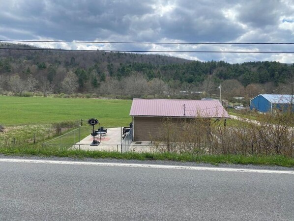 A small building with a red roof, a basketball hoop, and a picnic table.