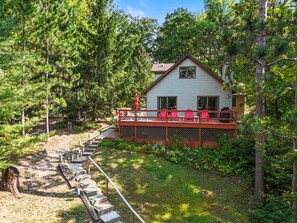 A cabin with a deck and outdoor seating, surrounded by dense forest.