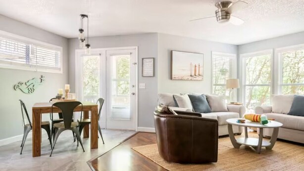 A spacious living room with a dining area, a sofa, a coffee table, and a fireplace. - Cheerful Sound Side Condo (Kill Devil Hills)