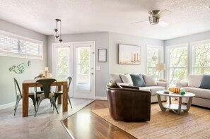 A spacious living room with a dining area, a sofa, a coffee table, and a fireplace. - Cheerful Sound Side Condo (Kill Devil Hills)