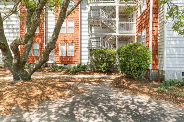 A multi-story building with a brick facade and white railings on the balconies. - Cheerful Sound Side Condo (Kill Devil Hills)