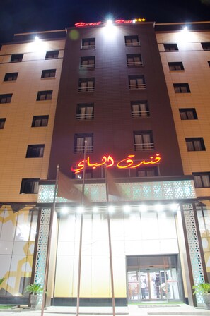 A hotel with a prominent sign in Arabic and English, multiple windows, and a well-lit entrance.