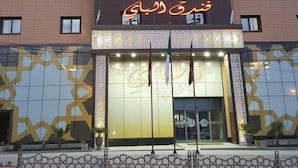 A hotel with a modern facade, multiple windows, and a prominent entrance with illuminated signage. - Hotel Elbey Constantine (Constantine)