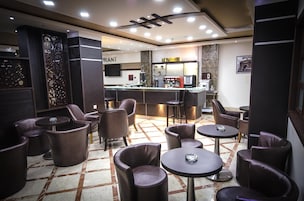 Un área de lounge moderna con asientos de cuero, bar y estación de café.