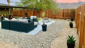 A backyard with a patio, outdoor seating, and a wooden fence. - NEW! Joshua Tree Dream - A Modern Desert Spa Retreat (Twentynine Palms)