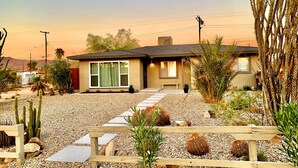 A single-story house with a sloped roof, a front porch, and a gravel driveway. - NEW! Joshua Tree Dream - A Modern Desert Spa Retreat (Twentynine Palms)