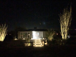 Une maison la nuit, avec une entrée éclairée et une allée.