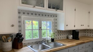 Une cuisine dotée d’un évier à deux bacs, d’un plan de travail en bois et de meubles de rangement gris.