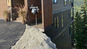 Ein modernes, mehrgeschossiges Haus mit Holzfassade, großen Fenstern und Blick auf den umliegenden Wald.