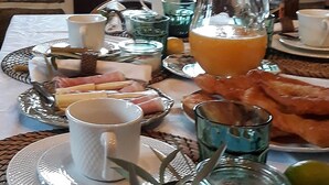 Una mesa de desayuno con pan, una jarra de jugo de naranja y varias tazas y vasos.