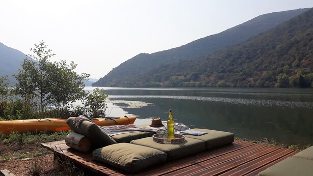 Un espacio de descanso junto al río, con vistas a un río y montañas.