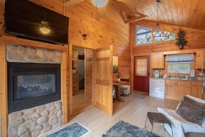 Ein gemütliches Blockhaus-Interieur mit Kamin aus Stein, Holzwänden, Essbereich und Küche.