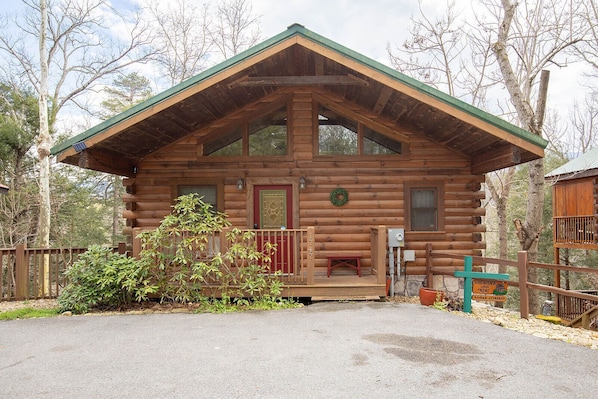 Eine Blockhütte mit Veranda, einer roten Tür und einer kleinen Bank.