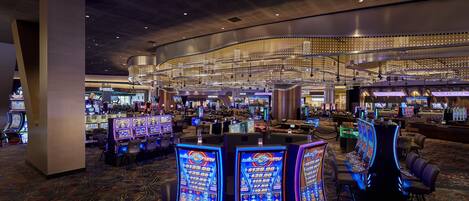 Un casino con numerosas máquinas tragamonedas y mesas de juego.