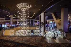 Eine großzügige Lobby mit einem zentralen Chandelier, Fahrtreppen und einem gemusterten Teppich.