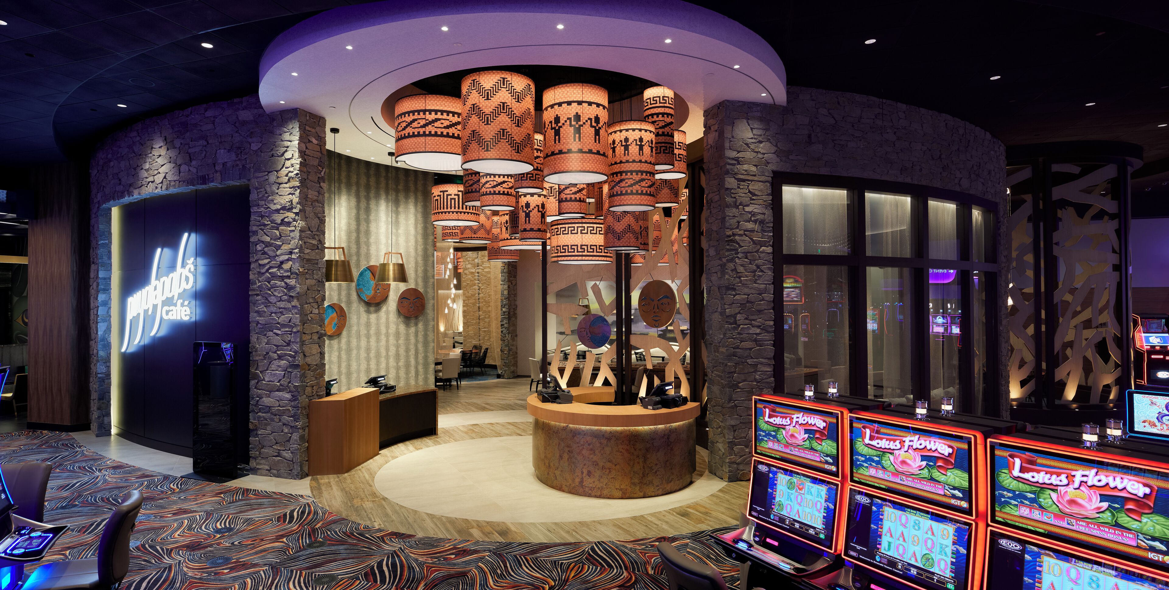 Un hall d’hôtel comprenant un comptoir d’accueil, un café et un espace de jeux avec des machines à sous.