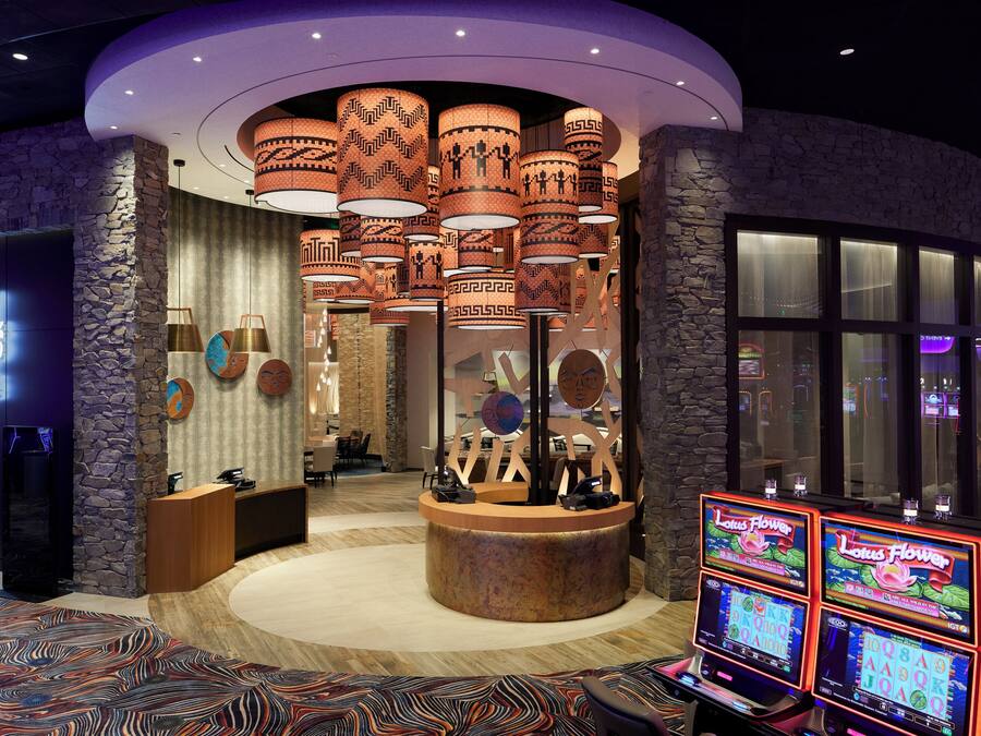 Un hall d’hôtel comprenant un comptoir d’accueil, un café et un espace de jeux avec des machines à sous.
