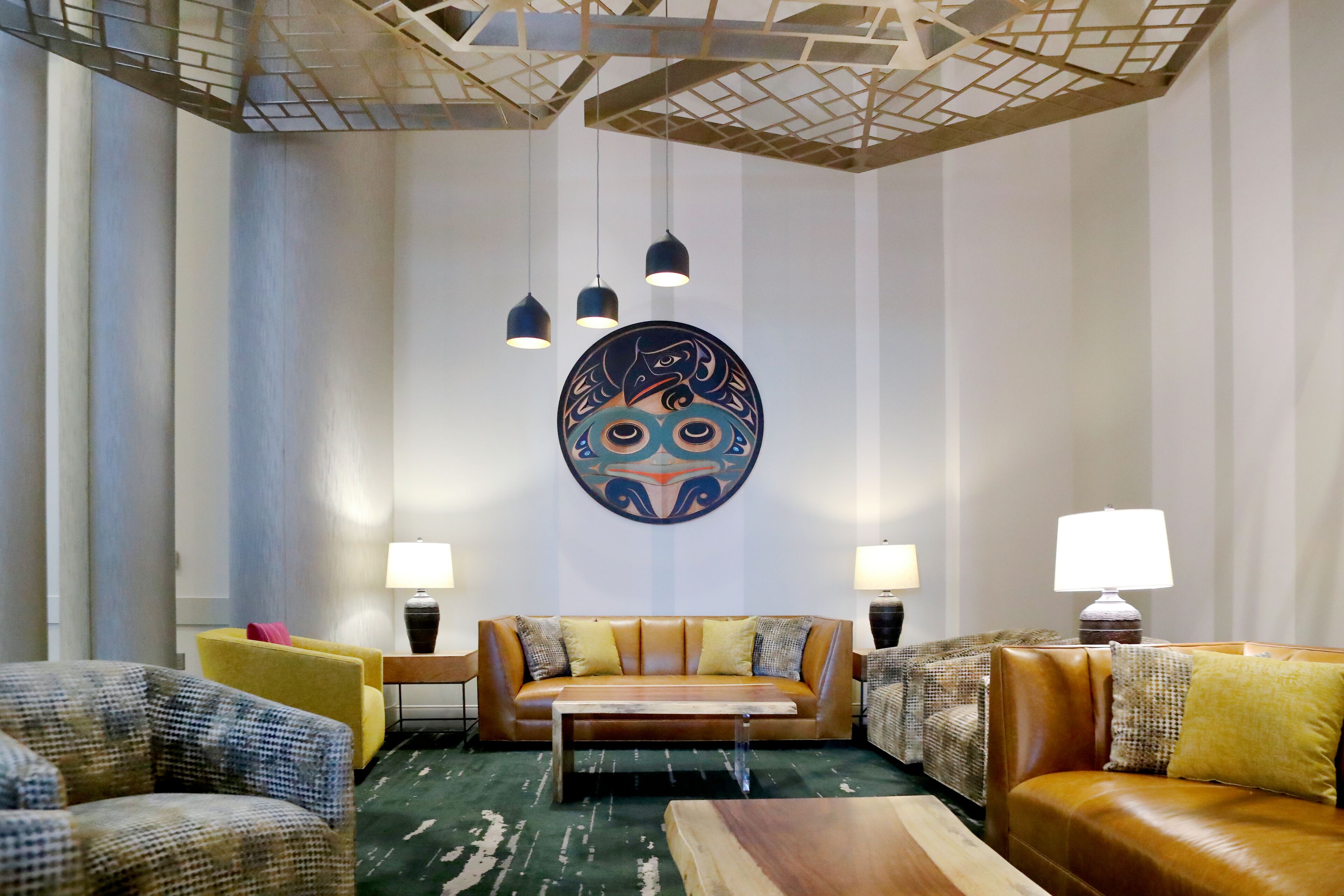 A modern living room with a leather sofa, patterned armchairs, and a coffee table.