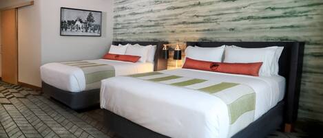 A hotel room with two beds, a large wall mural, and a patterned floor.