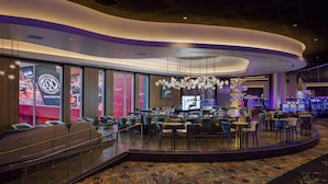 A modern casino hotel lobby with a curved seating area, large windows, and a chandelier. - Emerald Queen Hotel and Casino - Tacoma (Tacoma)