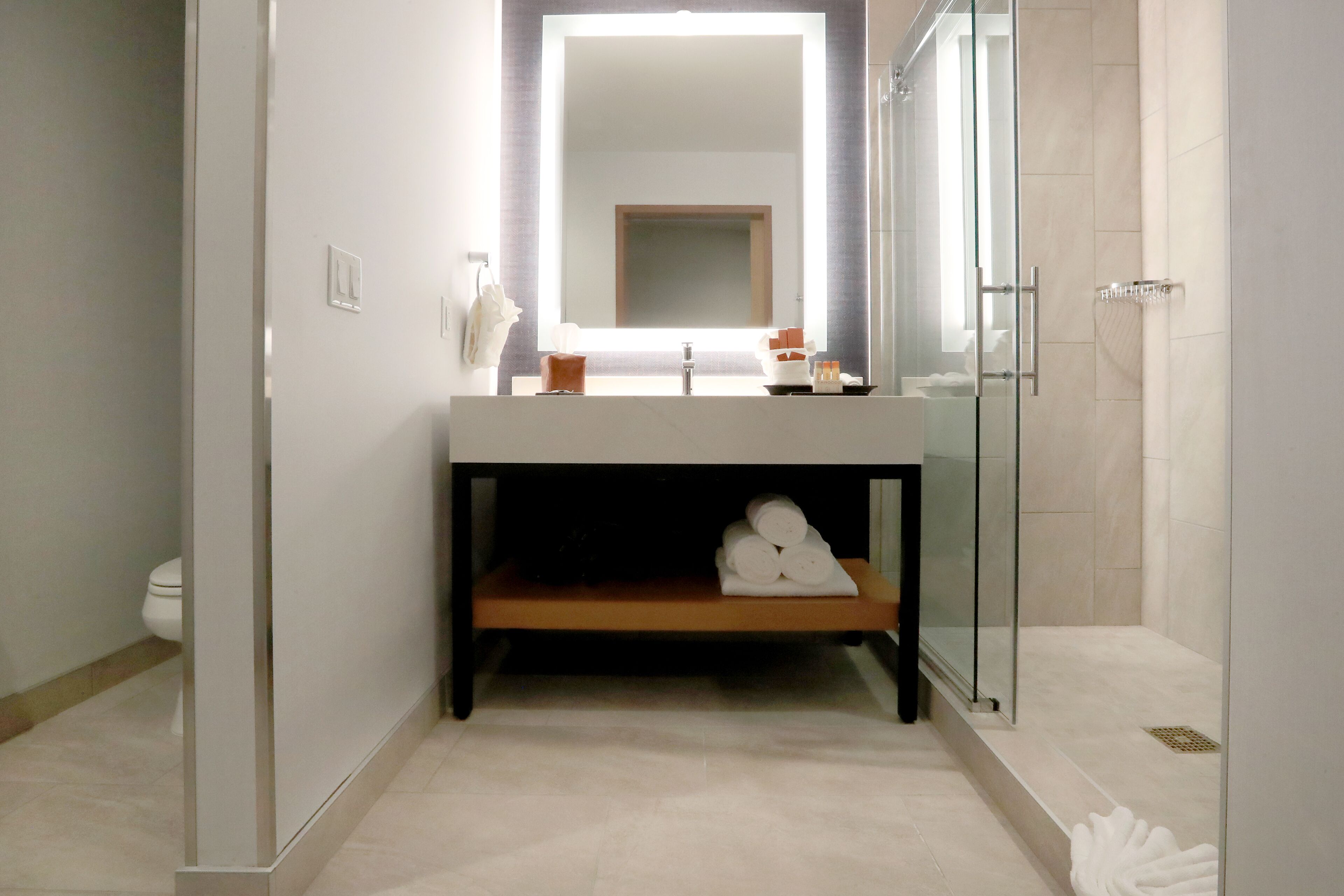 Une salle de bain moderne avec un grand miroir, un lavabo et une douche à parois de verre.