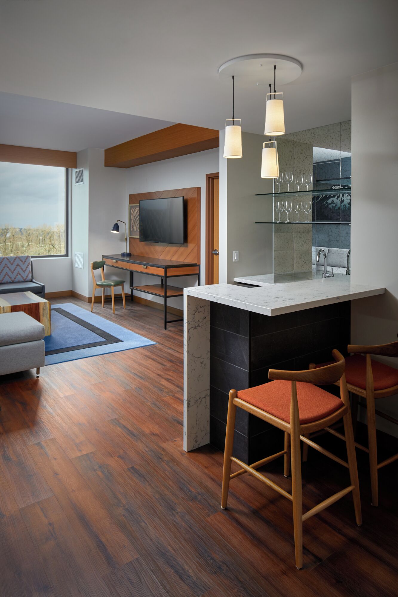 A modern kitchen with a marble countertop, wooden bar stools, and a built-in wine rack.