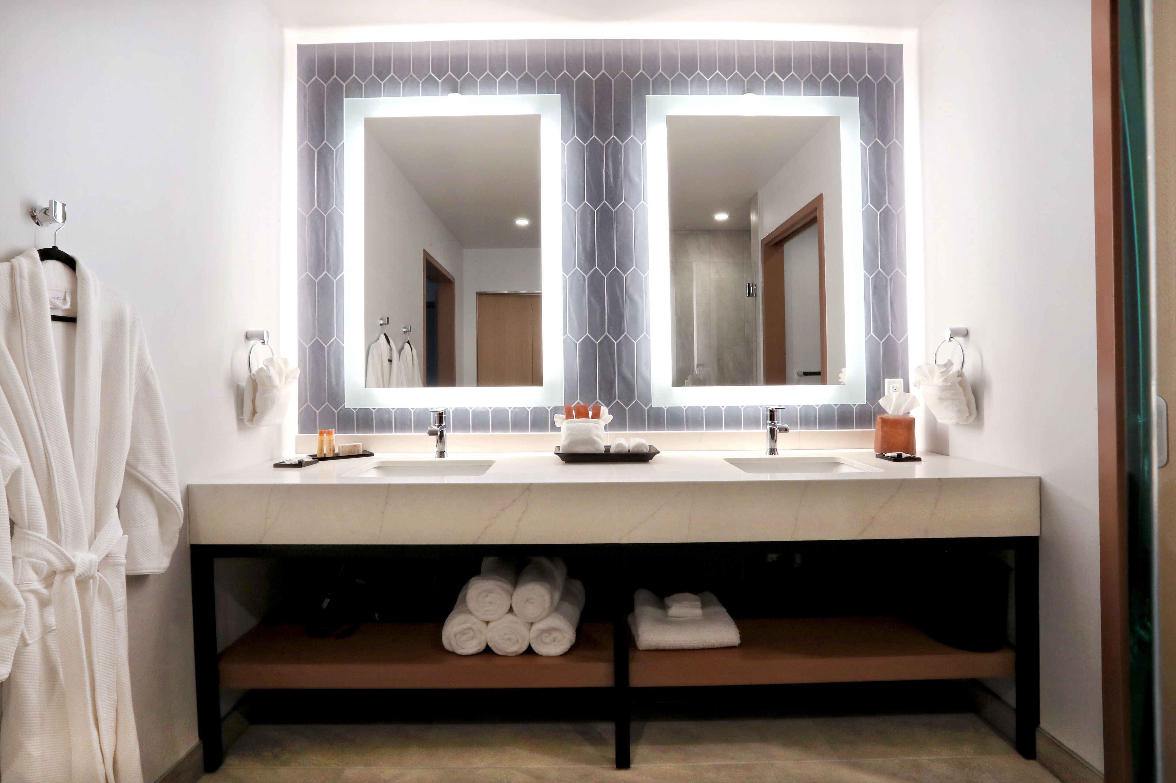 A bathroom with two sinks, a large mirror, and a towel rack.