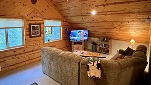 A cozy cabin interior with a wooden ceiling, a television, a sofa, and a fireplace. - Quiet and clean cabin near Yellowstone National Park (Island Park)