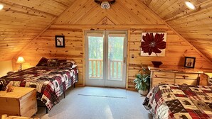 A cozy attic bedroom with two beds, a large window, and wooden walls. - Quiet and clean cabin near Yellowstone National Park (Island Park)