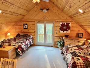 Ein gemütliches Schlafzimmer im Dachgeschoss mit zwei Betten, einem großen Fenster und Holzwänden.