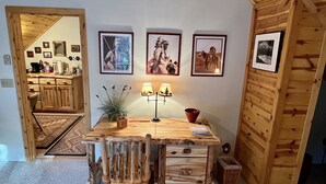 A rustic wooden dining area with a table, chairs, and a lamp. There are framed pictures on the wall and a plant on the table. - Quiet and clean cabin near Yellowstone National Park (Island Park)