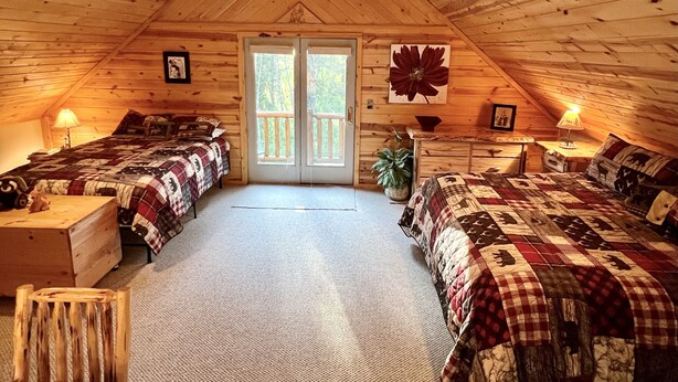 A cozy attic bedroom with two beds, a ceiling fan, and a large window. - Quiet and clean cabin near Yellowstone National Park (Island Park)