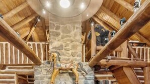 L’intérieur d’une cabane en rondins, avec une cheminée en pierre, des poutres en bois et un canapé en cuir.