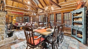 L’intérieur d’une cabane en rondins comprend un coin repas, des murs en pierre, des poutres en bois et un lustre.