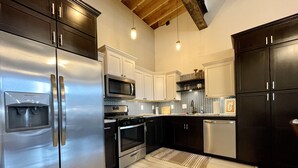 A modern kitchen with stainless steel appliances, white cabinetry, and a herringbone tile backsplash. - Historic 1 bed 1 bath in 1920's Chevy (Mountain Home, AR, 72653)