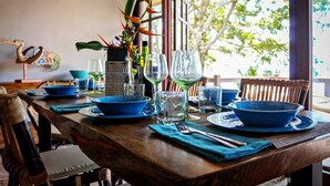 Una mesa de comedor dispuesta con cuencos azules, copas de vino y una planta decorativa.