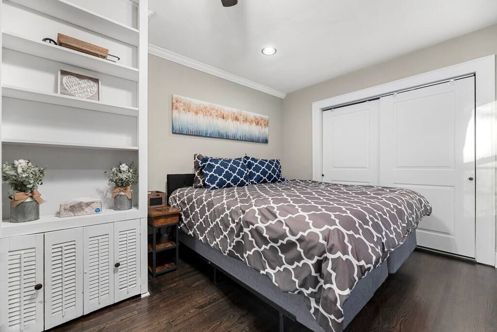 Een slaapkamer met een bed, een kledingkast, een plank met decoratieve objecten en een schilderij aan de muur.