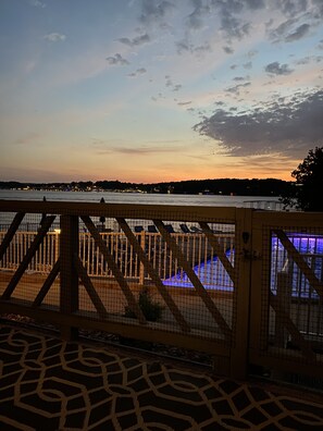 A sunset view from a gated area with a pool illuminated in blue.