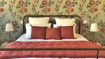 Een bed met een houten frame, witte beddengoed en rode kussens.