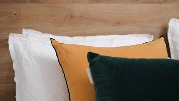 A bed with white and colored pillows against a wooden headboard.