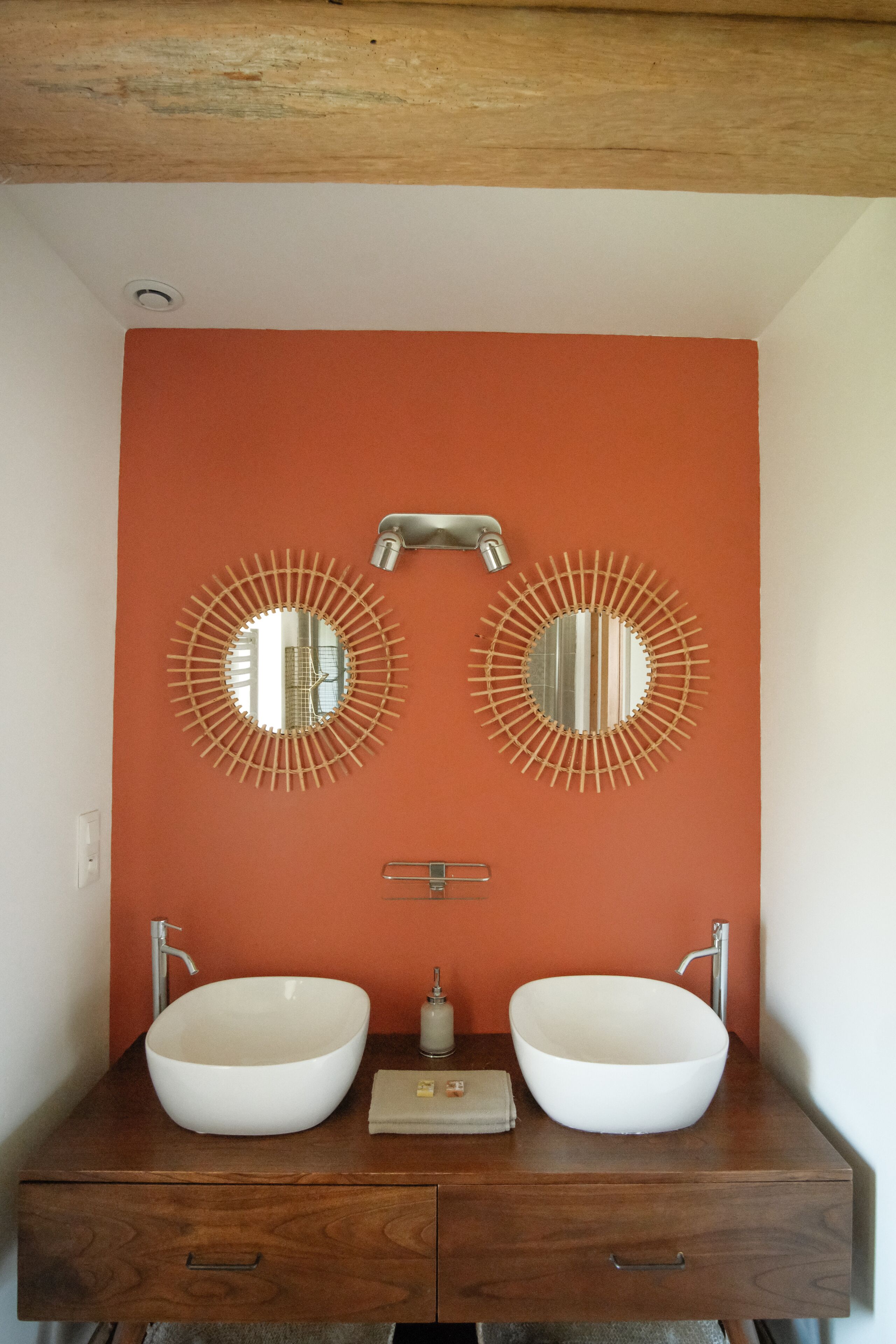 A bathroom with two sinks, a mirror, and a towel dispenser.