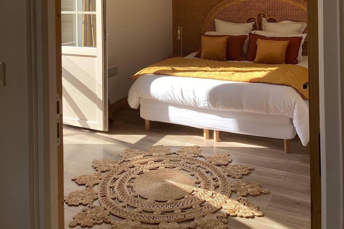 Une chambre à coucher avec un lit, un luminaire suspendu et un tapis à motifs.