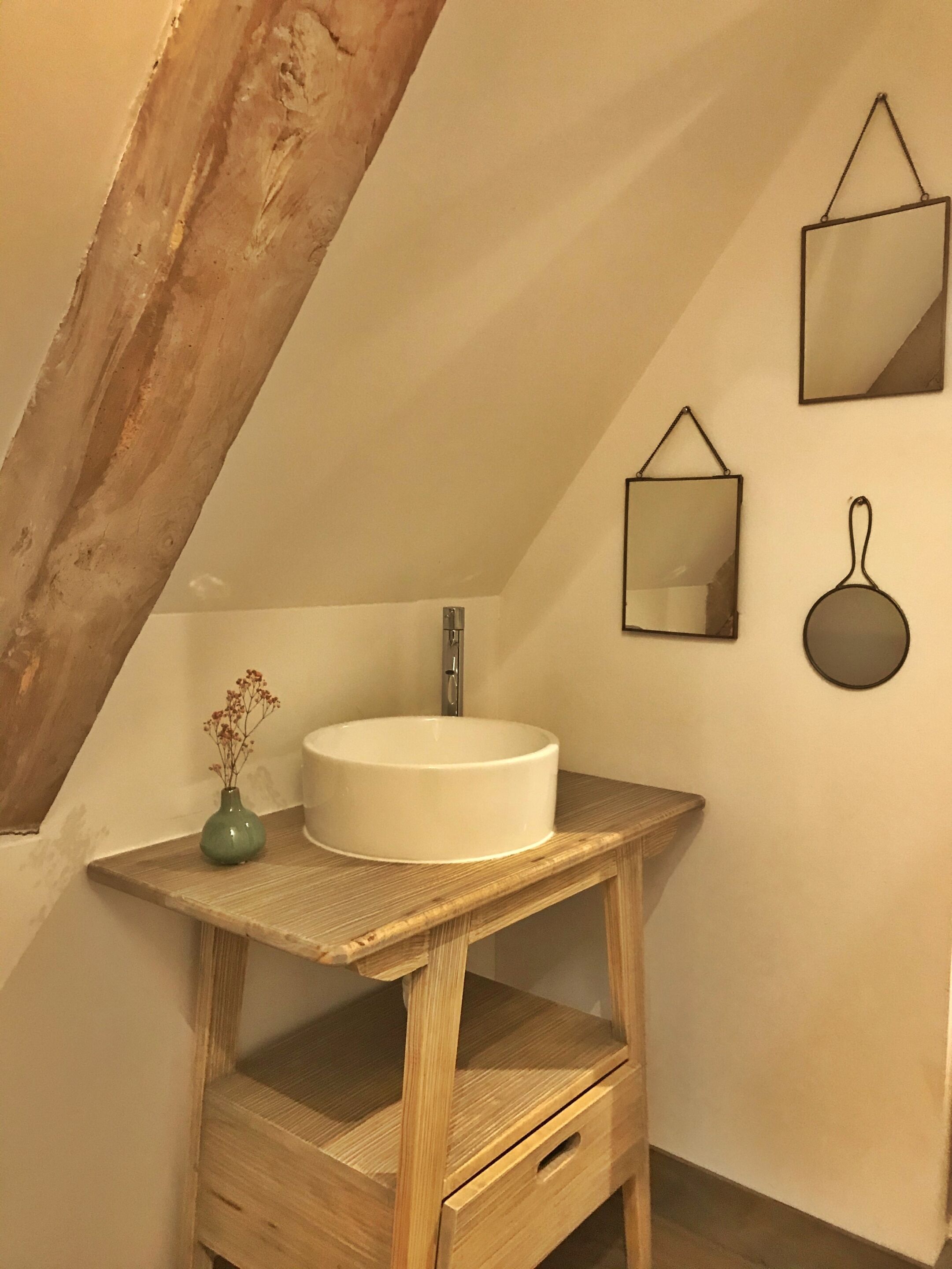 Een badkamer met een houten wastafelmeubel, een witte wastafel en een spiegel.