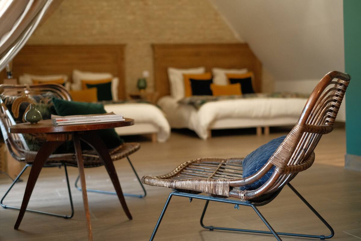Une pièce confortable avec un lit, un fauteuil en osier et une petite table.