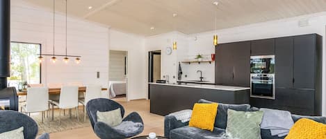 A modern living space with a sofa, chairs, a coffee table, and a kitchen area.