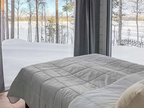 Une chambre avec une grande fenêtre donnant sur un paysage enneigé et des arbres.
