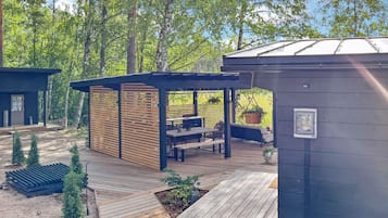 A wooden deck with outdoor furniture, surrounded by a forest.