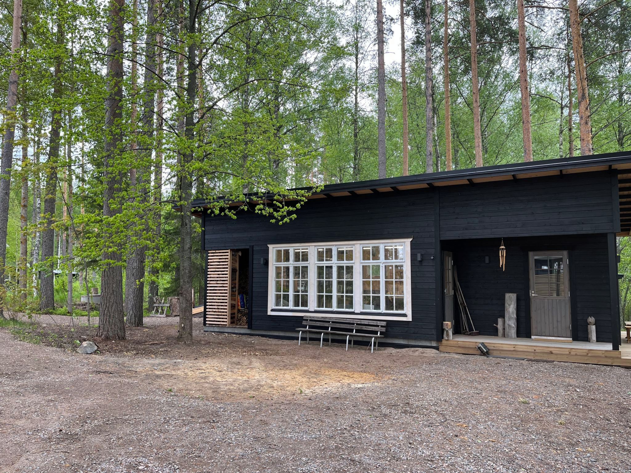 Une cabane dotée d’une grande fenêtre, d’un banc à l’extérieur et entourée d’une forêt.